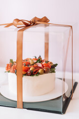 Salty cake with mushrooms decorated with salami olives in a large transparent box.