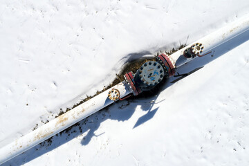 Aerial view of a pipeline with a value and coupling in a snow-covered field, West of Calgary; Alberta, Canada