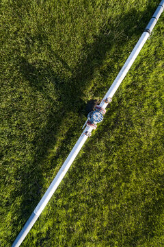 Aerial view of a pipeline with a value and coupling in a green field, West of Calgary; Alberta, Canada