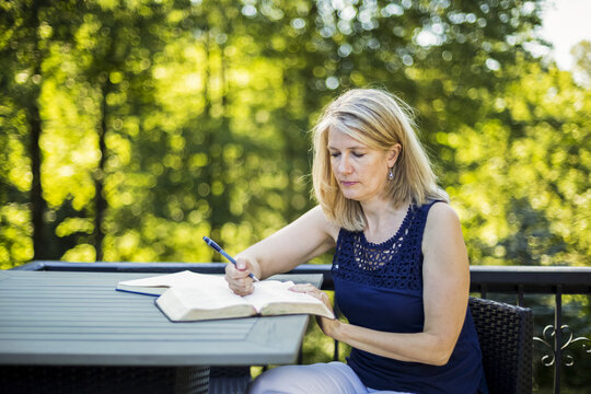 A woman reading her Bible outside on her deck; Surrey, British Columbia, Canada