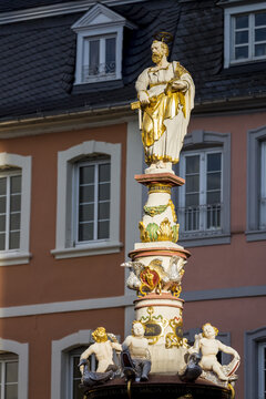 Decorative St. Peter's fountain and statues with gold trim in city square; Trier, Germany