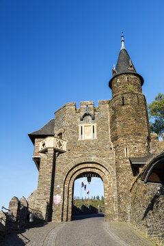 Old medieval stone castle archway wall entrance with turret and blue sky; Cochem, Germany