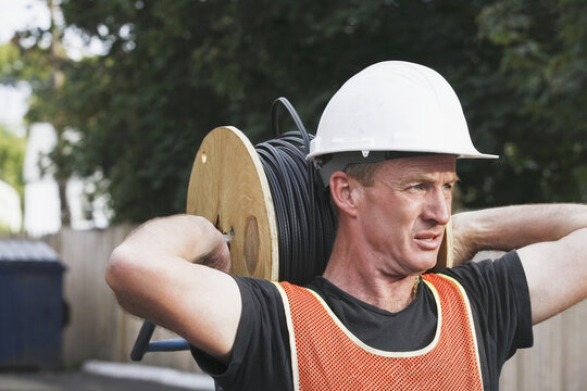 Lineman carrying a cable spool