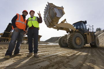 Two engineers near a front-end loader at an asphalt plant