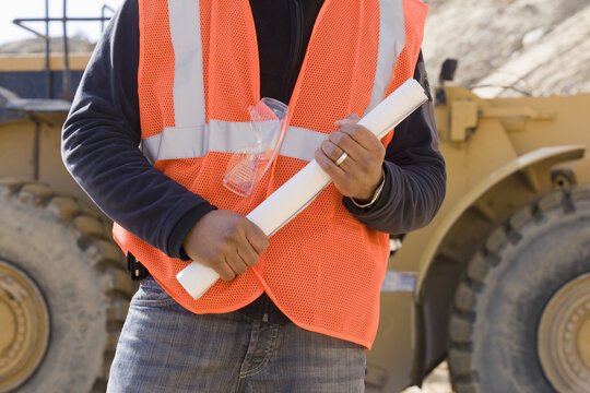 Engineer holding a blueprint at a construction site