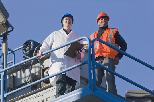 Lab worker standing with an engineer at an asphalt plant