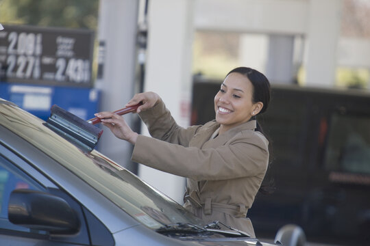 Hispanic woman washing the windshield of a car