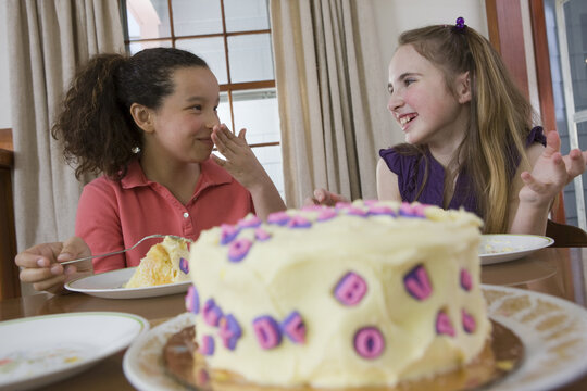 Two girls eating birthday cake and smiling