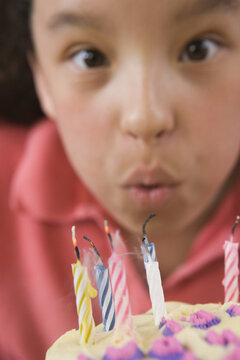 Hispanic girl blowing out candles on a birthday cake