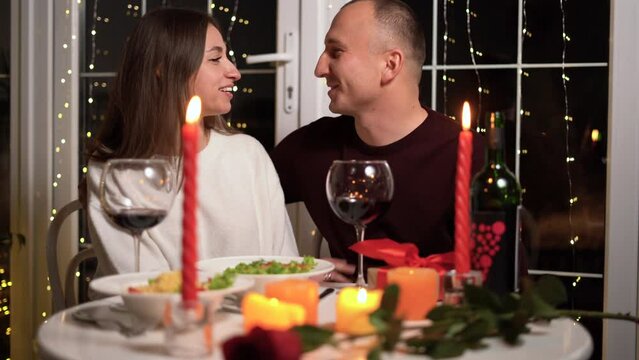 Romantic dinner setting, red wine in glasses and candles, date for two, Valentine's Day evening, burning candles on the table