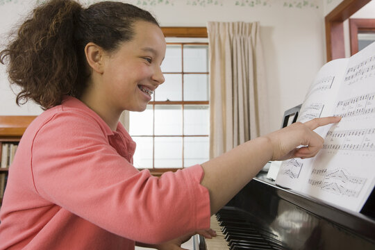 Hispanic girl reading a music sheet on a piano