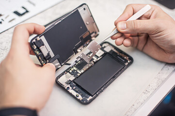 Cell phone repair at service center, smartphone disassembling and diagnostics, repairman workplace...
