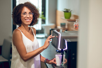 Company employee making herself a drink in the office kitchen