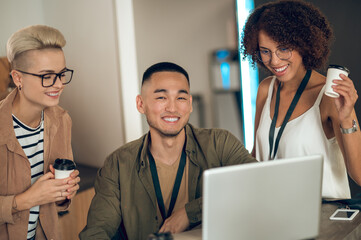 Cheerful team of multinational coworkers communicating during the coffee break
