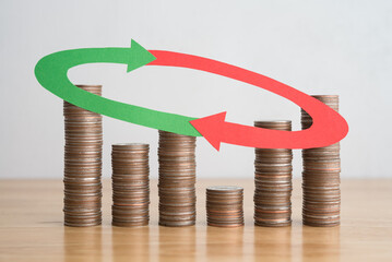 Stack coins and arrow red green curve graph chart volatility up and down on wooden table...