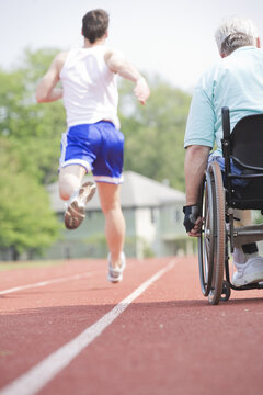 Rear view of runners racing on a racetrack.