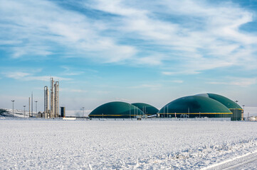 Moderne Biogasanlage in ländlicher, winterlicher Region vor blauem Himmel