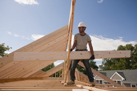 Carpenter carrying a roof rafter