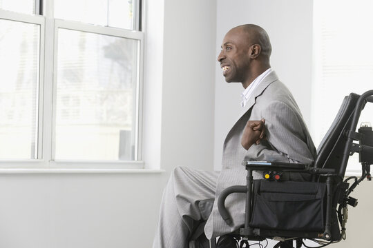 Businessman With Cerebral Palsy Looking Out Through The Office Window