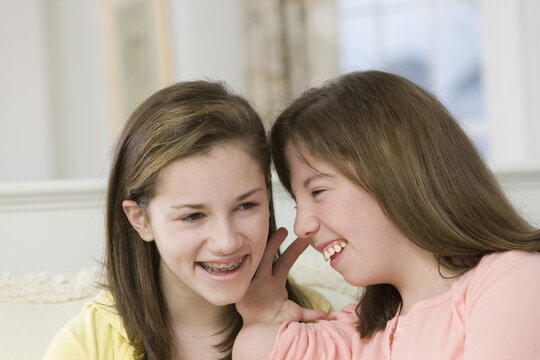 Teenage girl whispering to her sister, one with birth defect