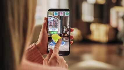 Decorating Apartment: Woman Holding Smartphone, using Augmented Reality Interior Design Software Chooses 3D Furniture for Home. Pick a Stylish Chair for the Living Room. Over Shoulder Close-up Screen