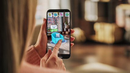 Decorating Apartment: Woman Holding Smartphone, using Augmented Reality Interior Design Software Chooses 3D Furniture for Home. Pick a Stylish Chair for the Living Room. Over Shoulder Close-up Screen