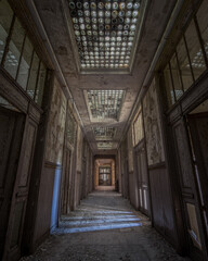 Vertical shot of the corridor of an old abandoned building with the decayed doors
