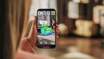 Decorating Apartment: Woman Holding Smartphone, using Augmented Reality Interior Design Software Chooses 3D Furniture for Home. Pick a Stylish Chair for the Living Room. Over Shoulder Close-up Screen