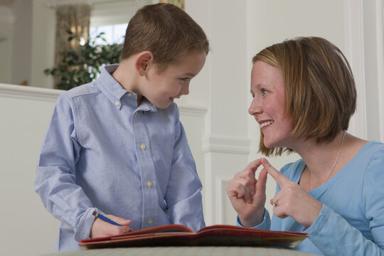 Woman signing the word 'Word' in American Sign Language while teaching her son