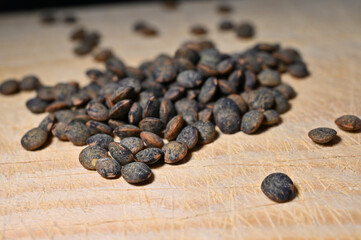 Dry Green French Lentils (Du Puy) on a wooden table, selective focus - some beans in focus, others not