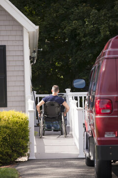 Man with spinal cord injury in a wheelchair going up home ramp
