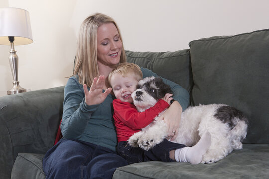 Woman signing the word 'Puppy' in American Sign Language while her son hugging a dog