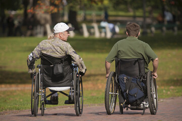 Two war veterans in wheelchairs in a park