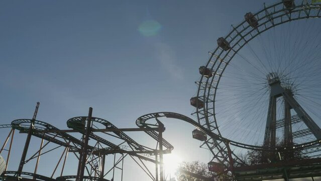 Sun behind roller coaster and Ferris wheel in the amusement park