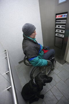 Woman with multiple sclerosis using an elevator with a service dog