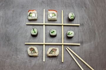 Sushi among chopsticks. Copy space. Brown background.