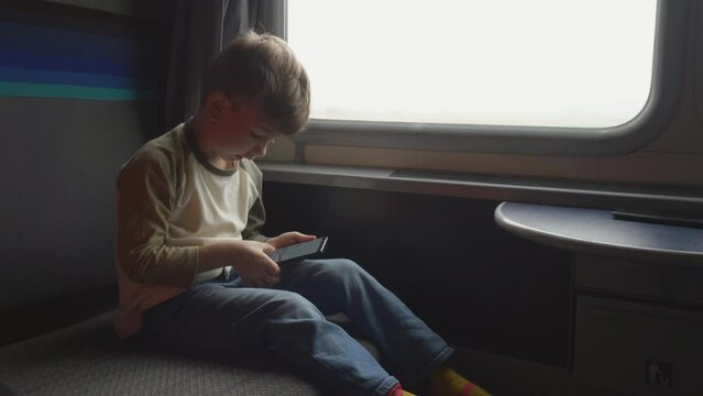 Little boy plays on mobile smart phone on train trip