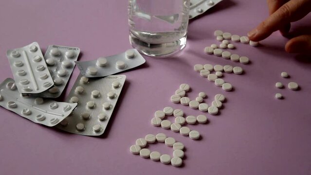 Pills on female hands. A woman with a mental disorder is about to commit suicide by poisoning herself with sleeping pills, folds the word Dream from the pills. Overdose and suicide concept.