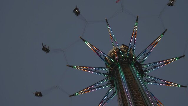 Sky flying chairs swinger with colorful lights spinning in the amusement park at sunset