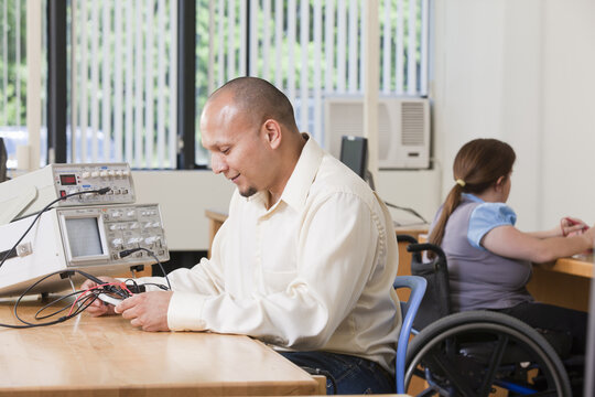 Engineering student inspecting circuit breadboard connections to oscilloscope and function generator