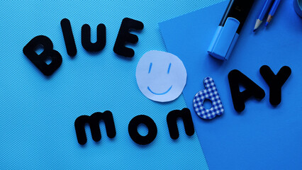 Letras de Blue Monday en fondo azul con una cara sonriente animada y material de papelería azul....