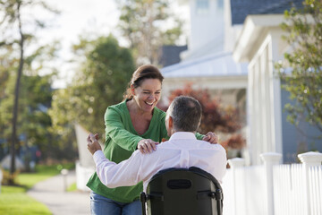 Couple happily greeting each other while he is in a wheelchair with a spinal cord injury