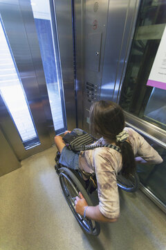 Woman with spinal cord injury in a wheelchair using elevator to train access