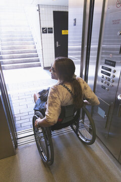 Woman with spinal cord injury in a wheelchair using elevator to train access