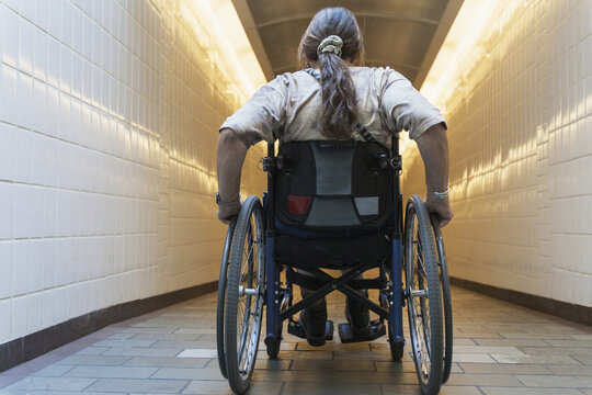 Woman with spinal cord injury in a wheelchair accessing subway train station