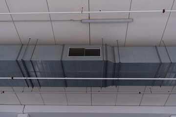 View of ventilation tube hanging on the ceiling and light of a commercial center. Ventilation...