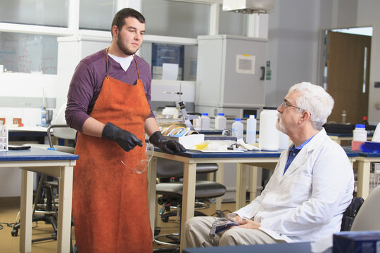 Professor with muscular dystrophy advising engineering student in a chemistry laboratory