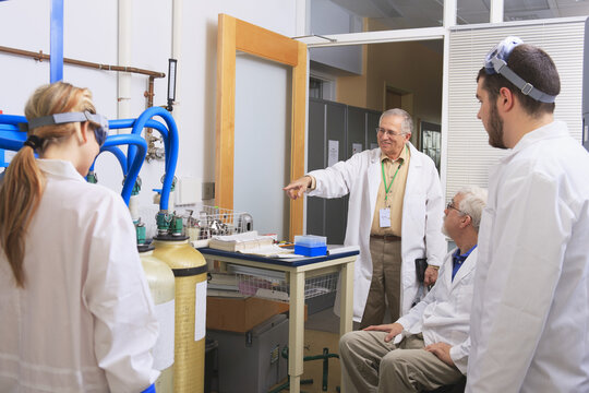 Professors talking to engineering students discussing water purification system for chemistry laboratory