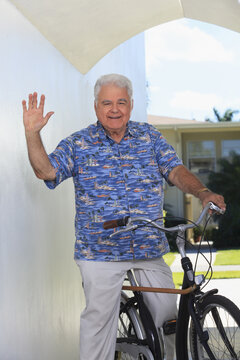 Senior man with polio waving his hand on bicycle with cane attached
