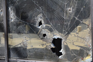 Broken glass of a street building. vandals smashed a shop window. Hooligans are breaking front...
